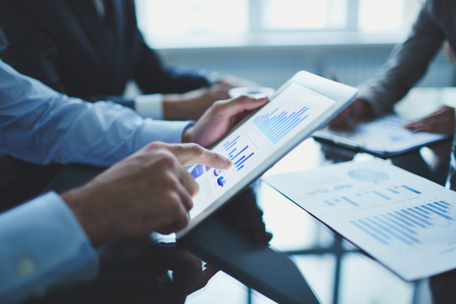 Businessman analyzing data charts on a digital tablet during a meeting | Webface