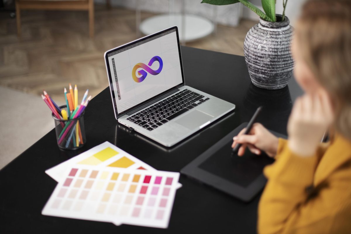 Graphic designer creating a colorful logo design on a laptop and graphic tablet for brand identity | Webface
