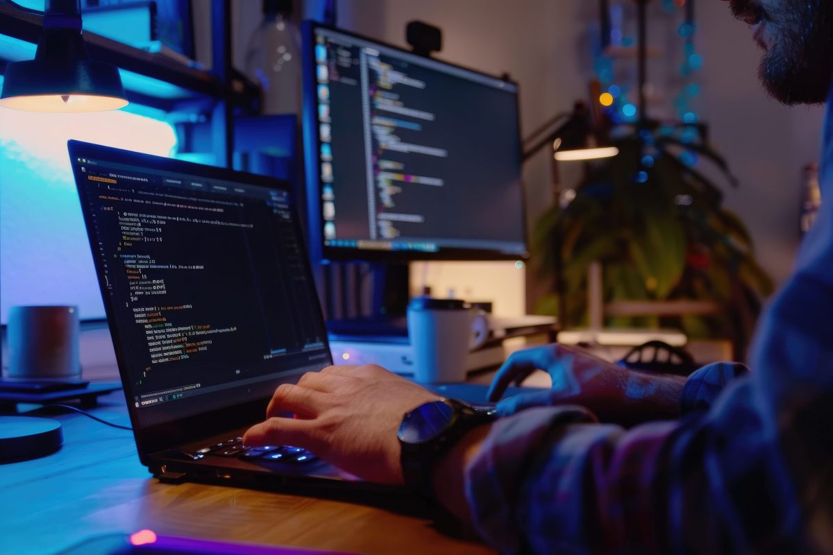 Web developer coding and programming websites on a laptop and multiple screens | Webface